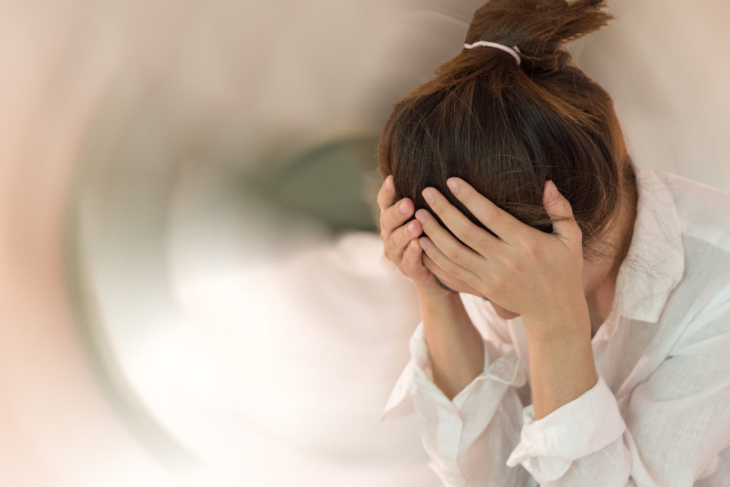 A picture of a woman with here head down and hands on her head, looking as if she is in distress.