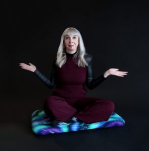 Picture of Diane Knoll, OTR/L sitting on a board that spins, called the astronaut board.